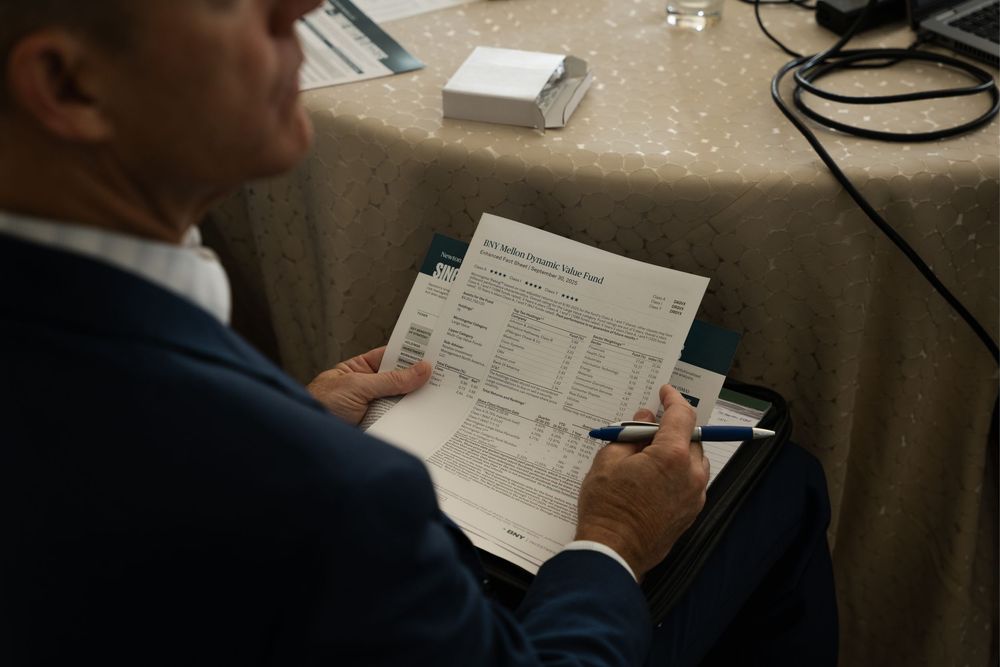 Business professional reviewing and signing documents on a clipboard at an elegant event table.