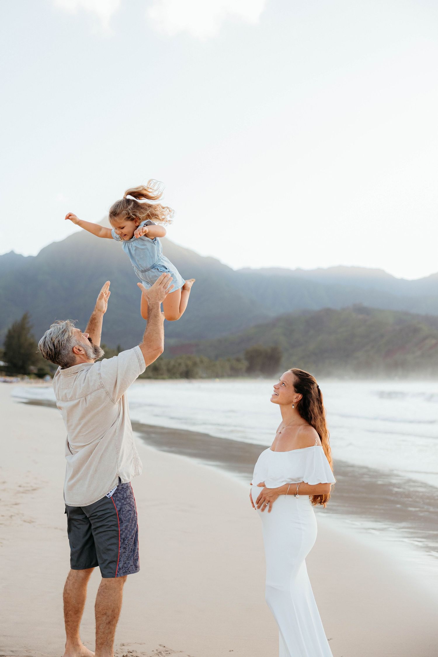 Candid family portraits in Hanalei Bay, Kauai with the beautiful mountains and ocean in the backdrop.