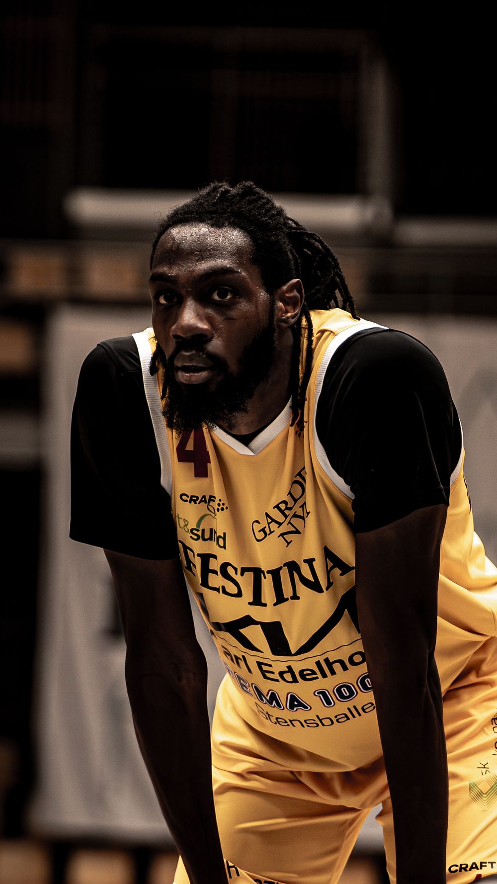 Basketball player wearing yellow Festina jersey number 4 with dreadlocks leaning forward during a game.