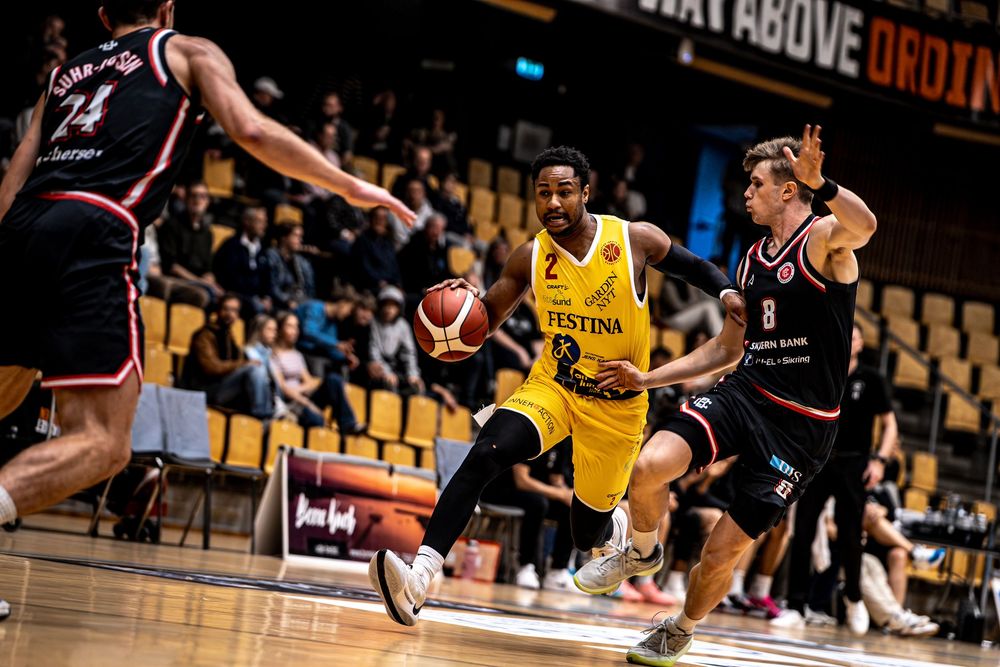 Basketball player wearing number 2 yellow jersey drives past defenders in a professional game.