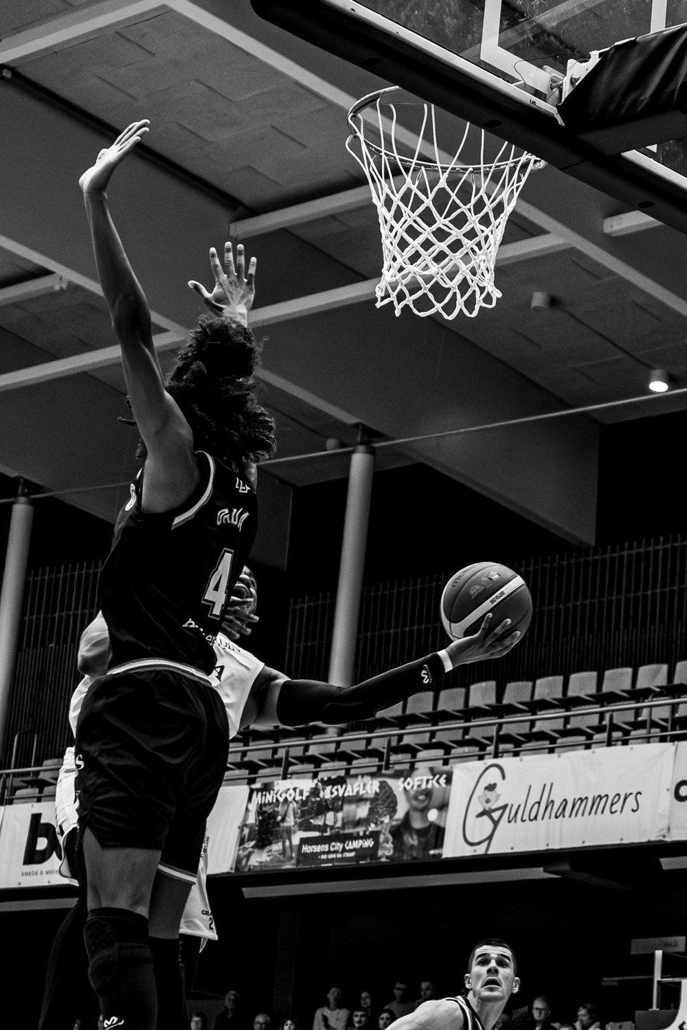 Black and white photo of basketball players competing near the hoop during an indoor game.