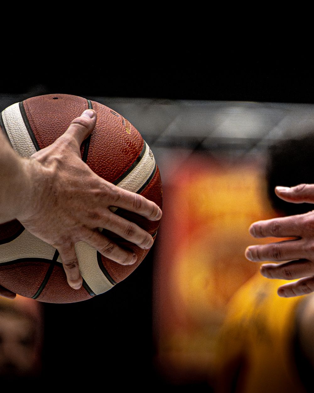 Close-up of hands gripping a basketball during a competitive game.