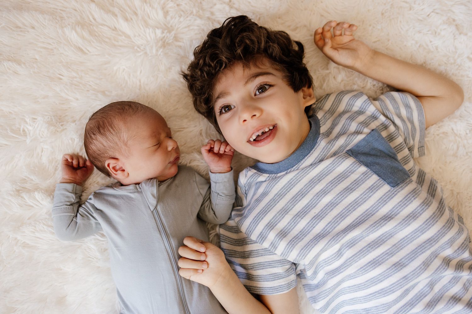 Newborn baby lays next to his big brother for their sibling headshot at their in-home newborn session in San Jose
