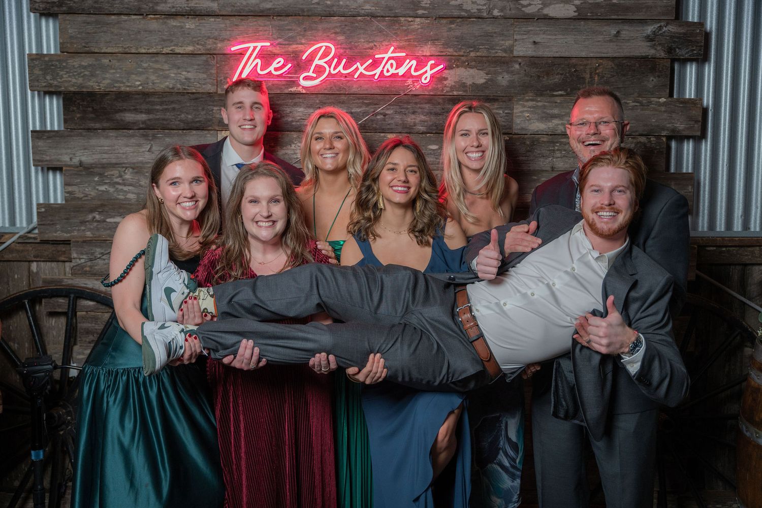 Guests posing together in front of a rustic wood and neon sign backdrop at a Rockin' H Ranch wedding in Palm City, FL