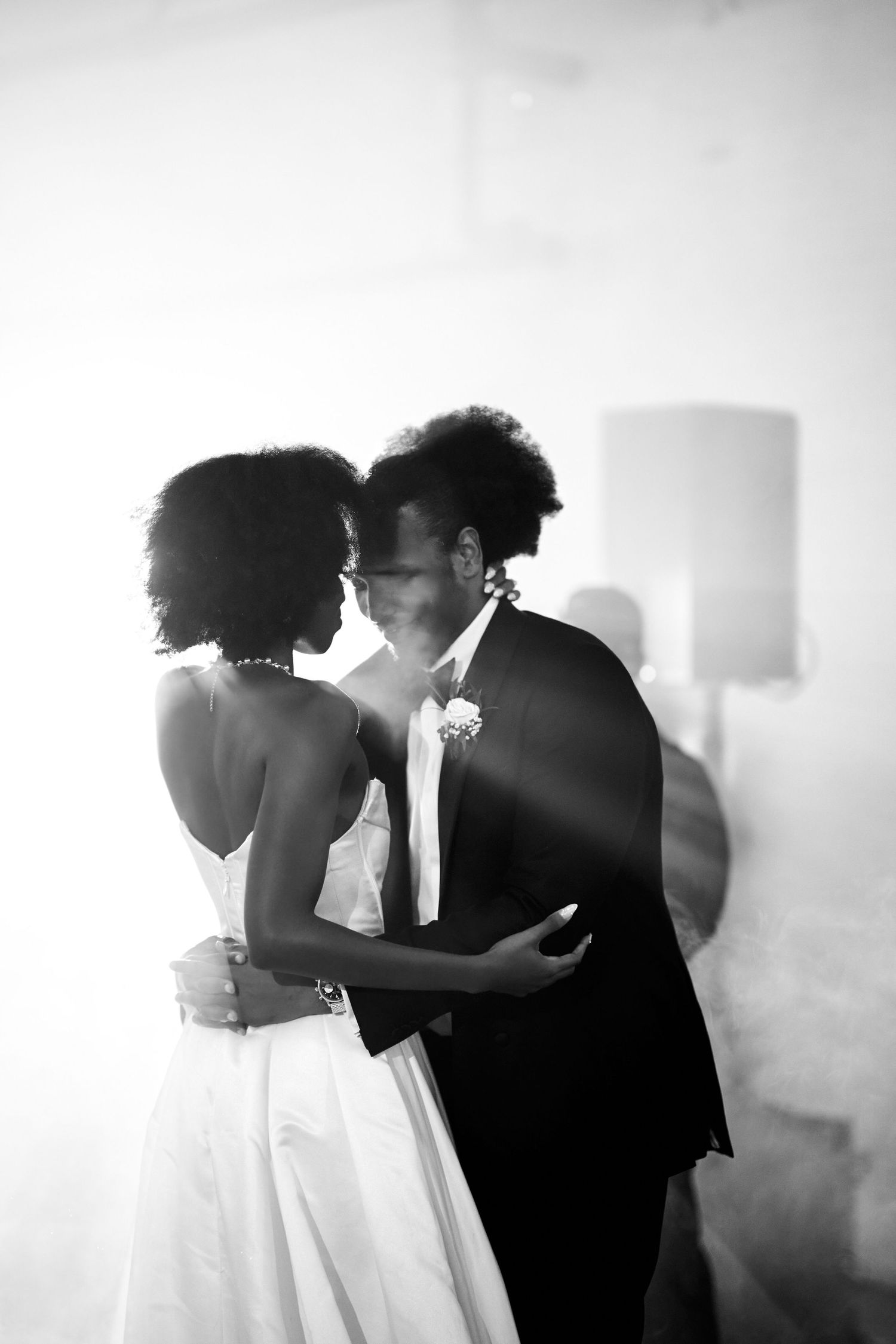 Black and white photo of a bride and groom sharing a romantic kiss during their first dance at wedding reception.