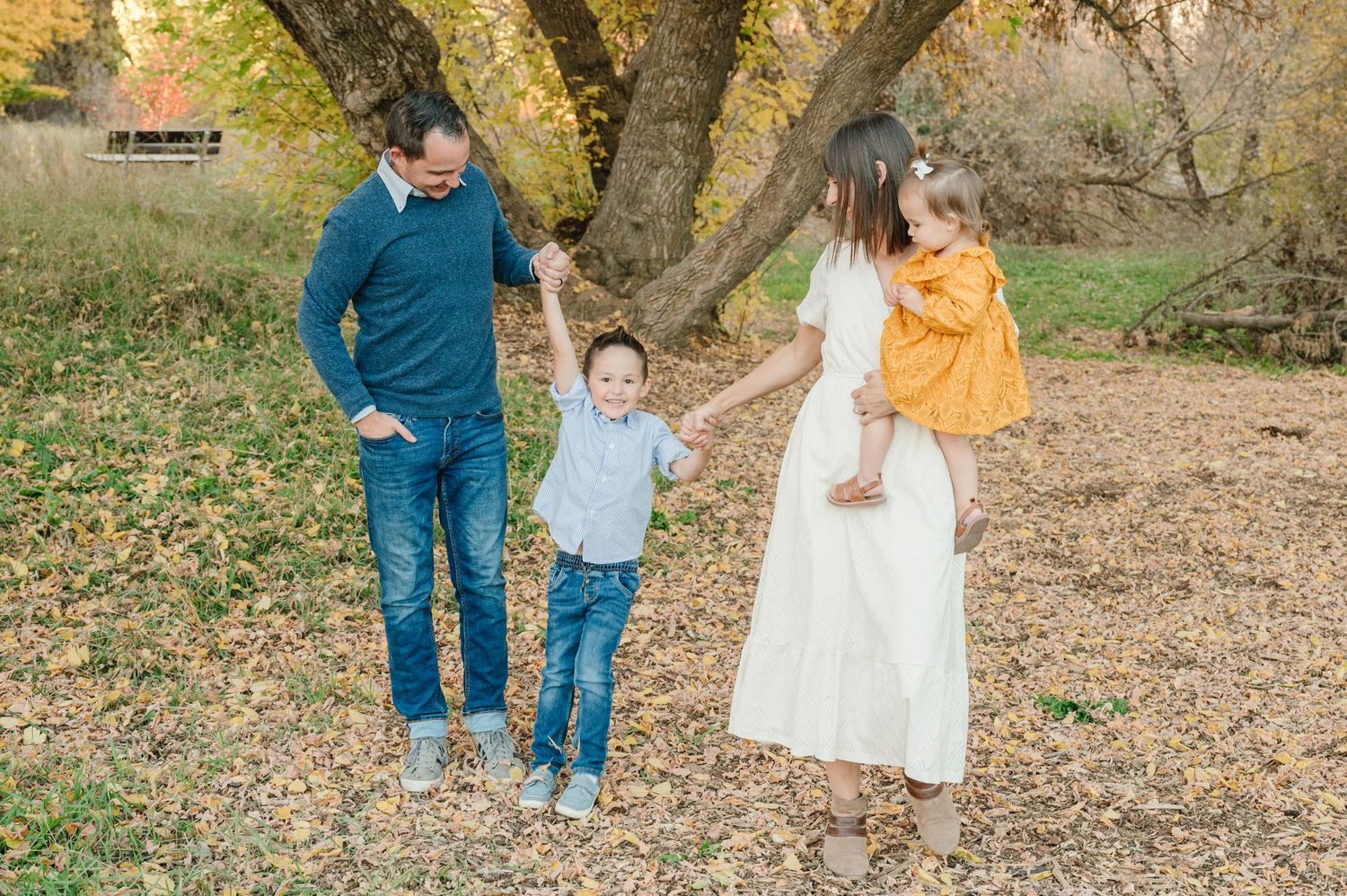 Family enjoying autumn scenery together under golden trees.