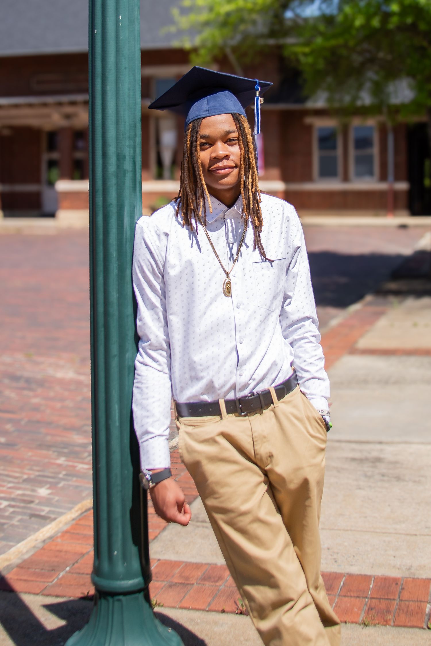 High school graduate boy leaning on post wearing cap