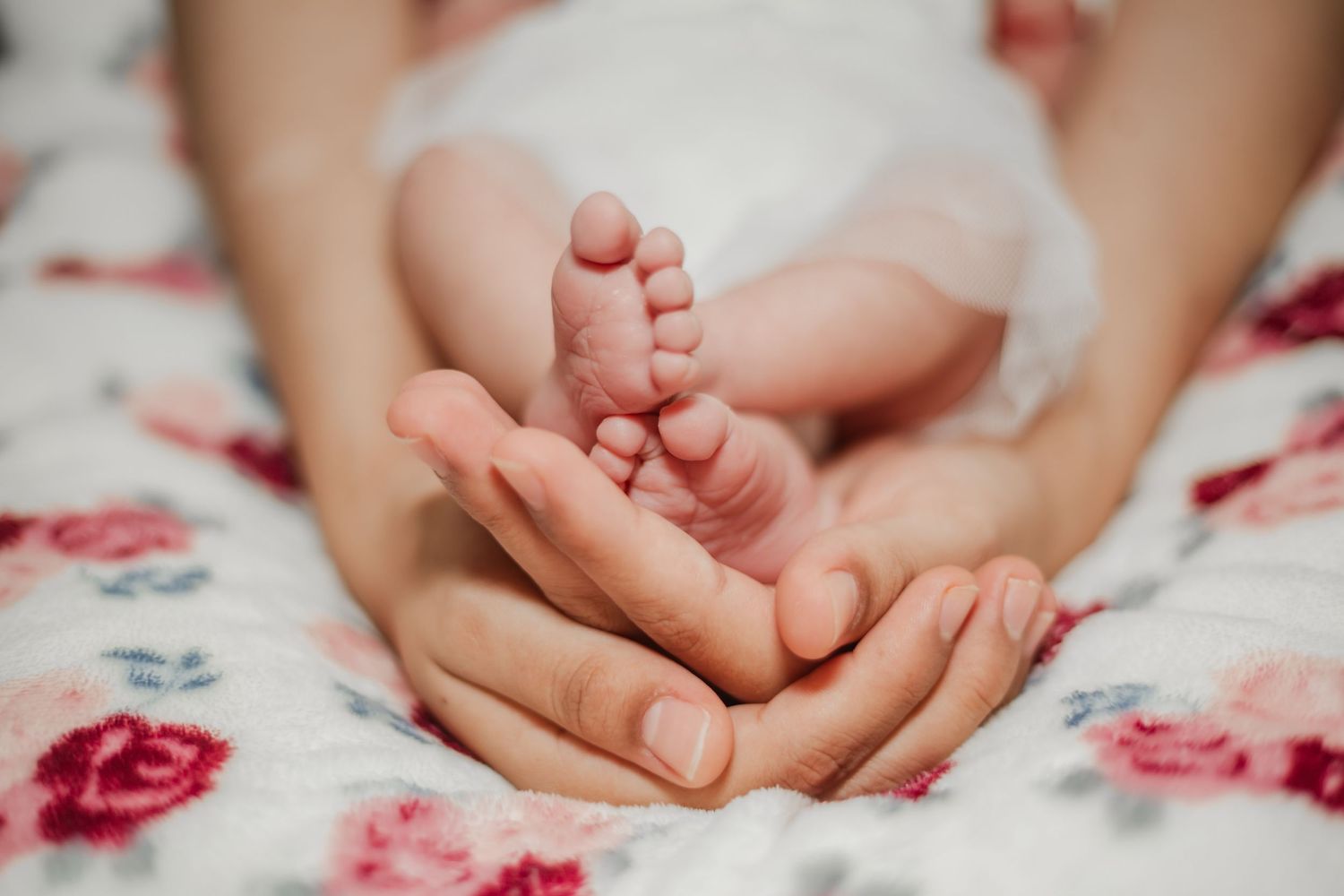 new born feet being held by mom's hands