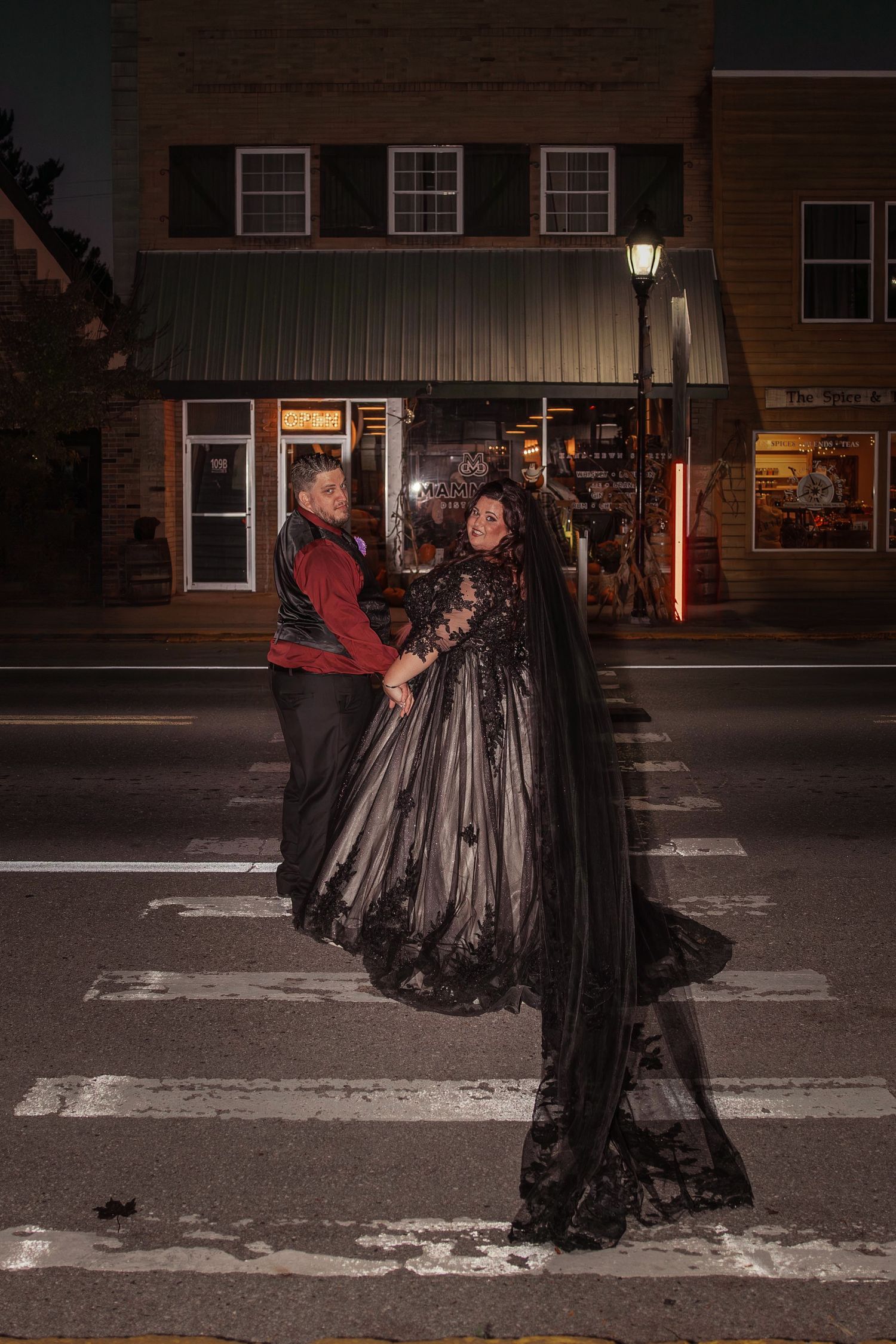 bride wearing black dress and groom in Belair Michigan crossing the street after reception