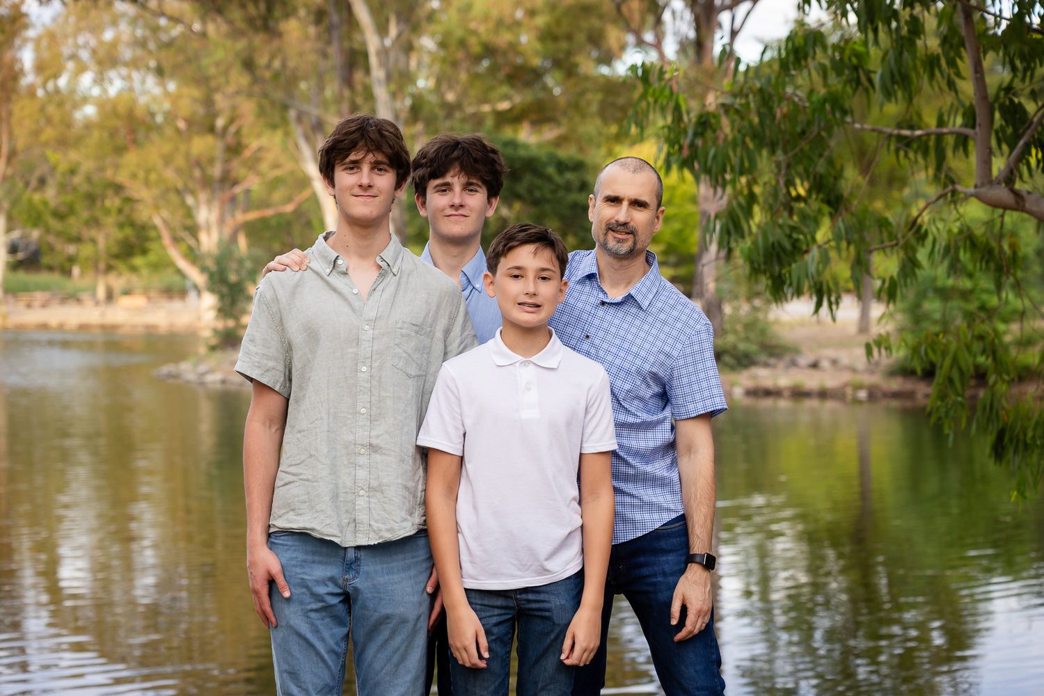 A family smiles in front of a lake background