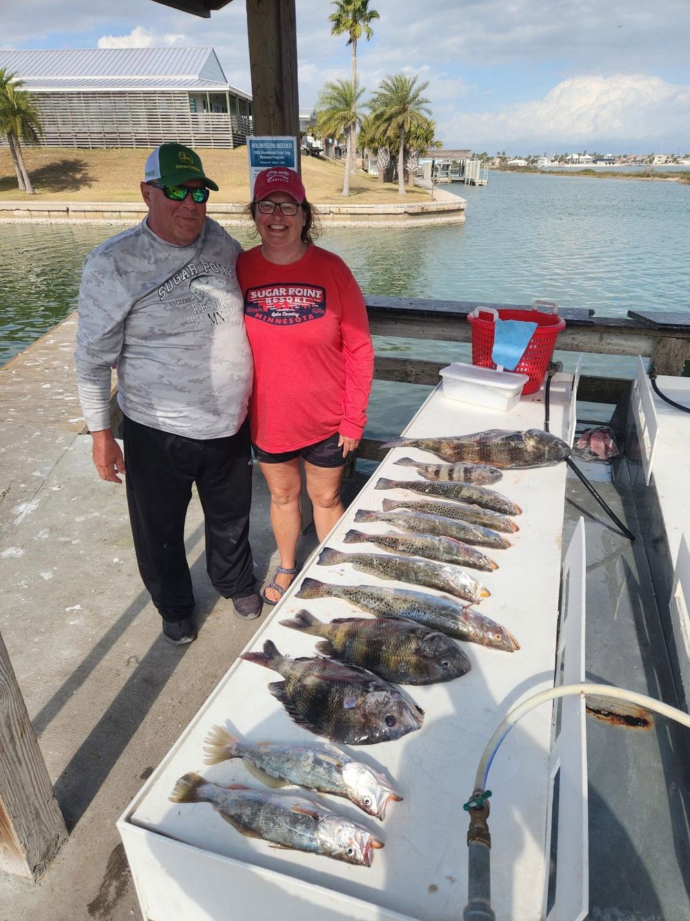 Couple posing with fresh catch of fish displayed on a cleaning table at a Texas coastal marina.