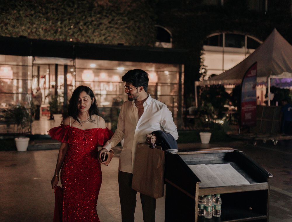 Couple in festive attire walking together at an elegant outdoor evening event.