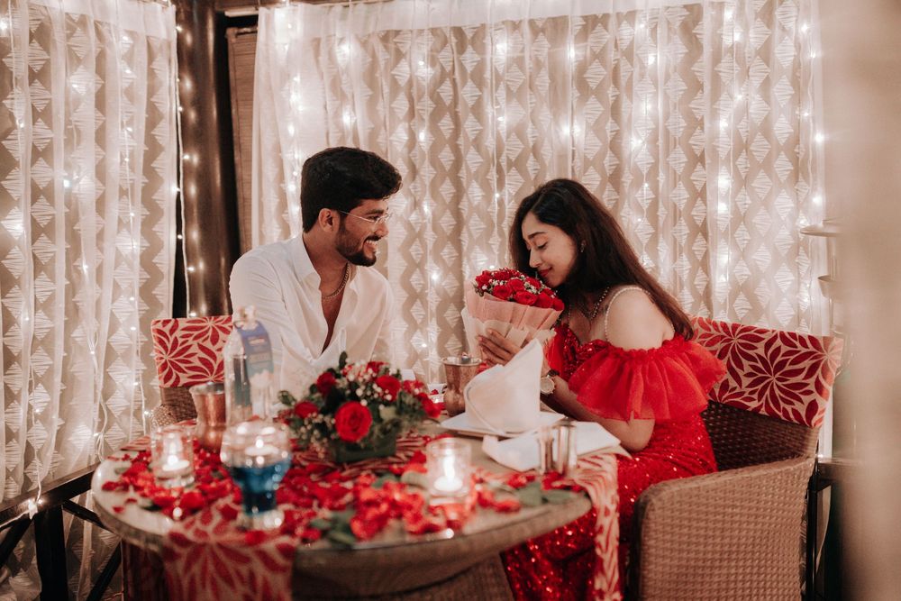 Couple enjoying an intimate romantic dinner with rose petals and candles at night.