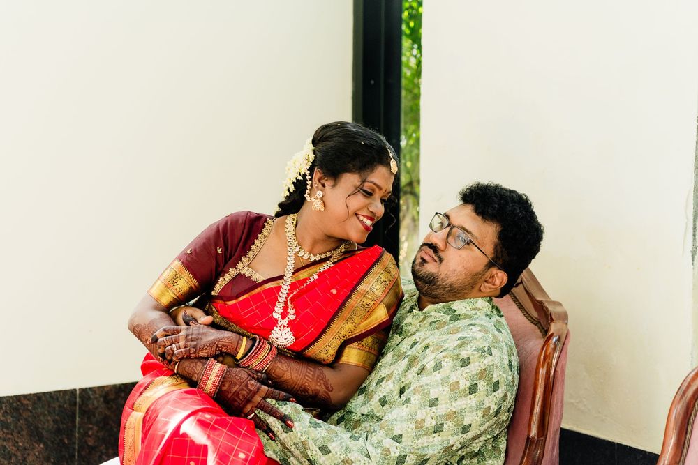 Indian bride in red saree and groom in green shirt sharing a tender moment during traditional wedding celebration.
