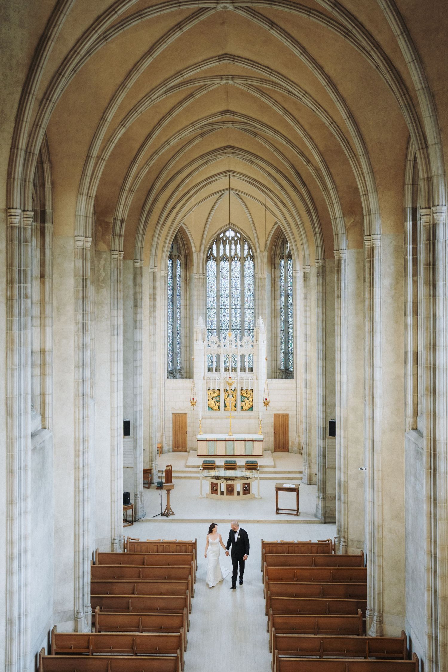 Couple poses in gothic archway with dramatic windows and natural light.