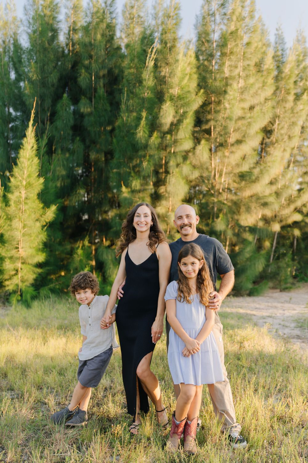 Family of 4 posing for portrait at sunset session in a field