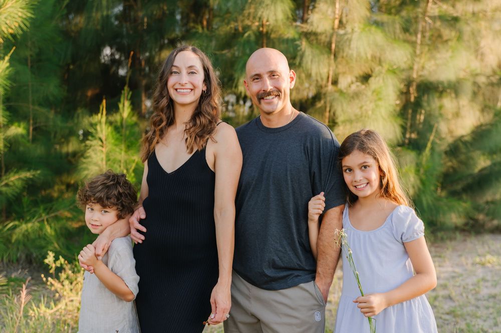 family of four smiling at sunset, golden hour session.