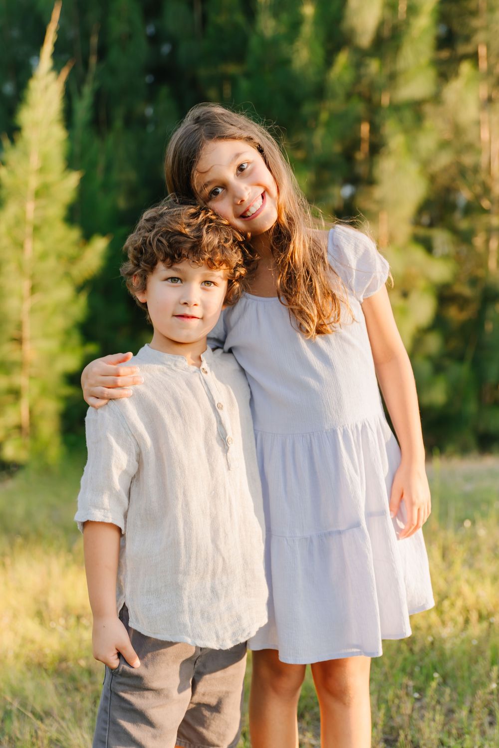 golden hour sibling posing photo outside in a field