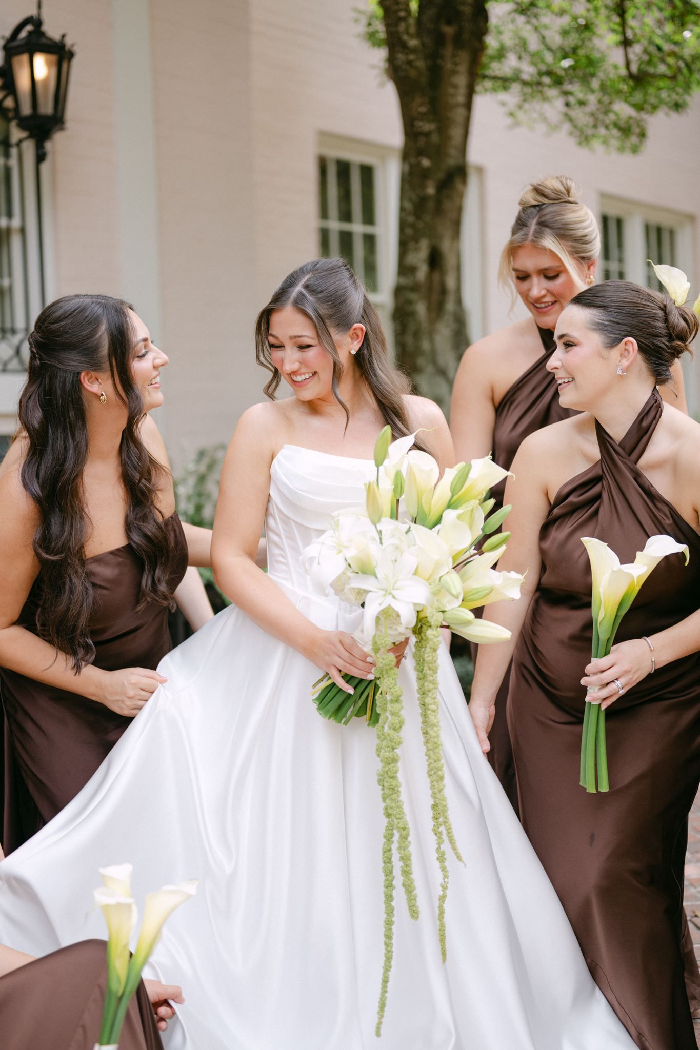 Bridesmaids fluffing bride's dress in front of the River Oaks Garden Club in Houston Texas.