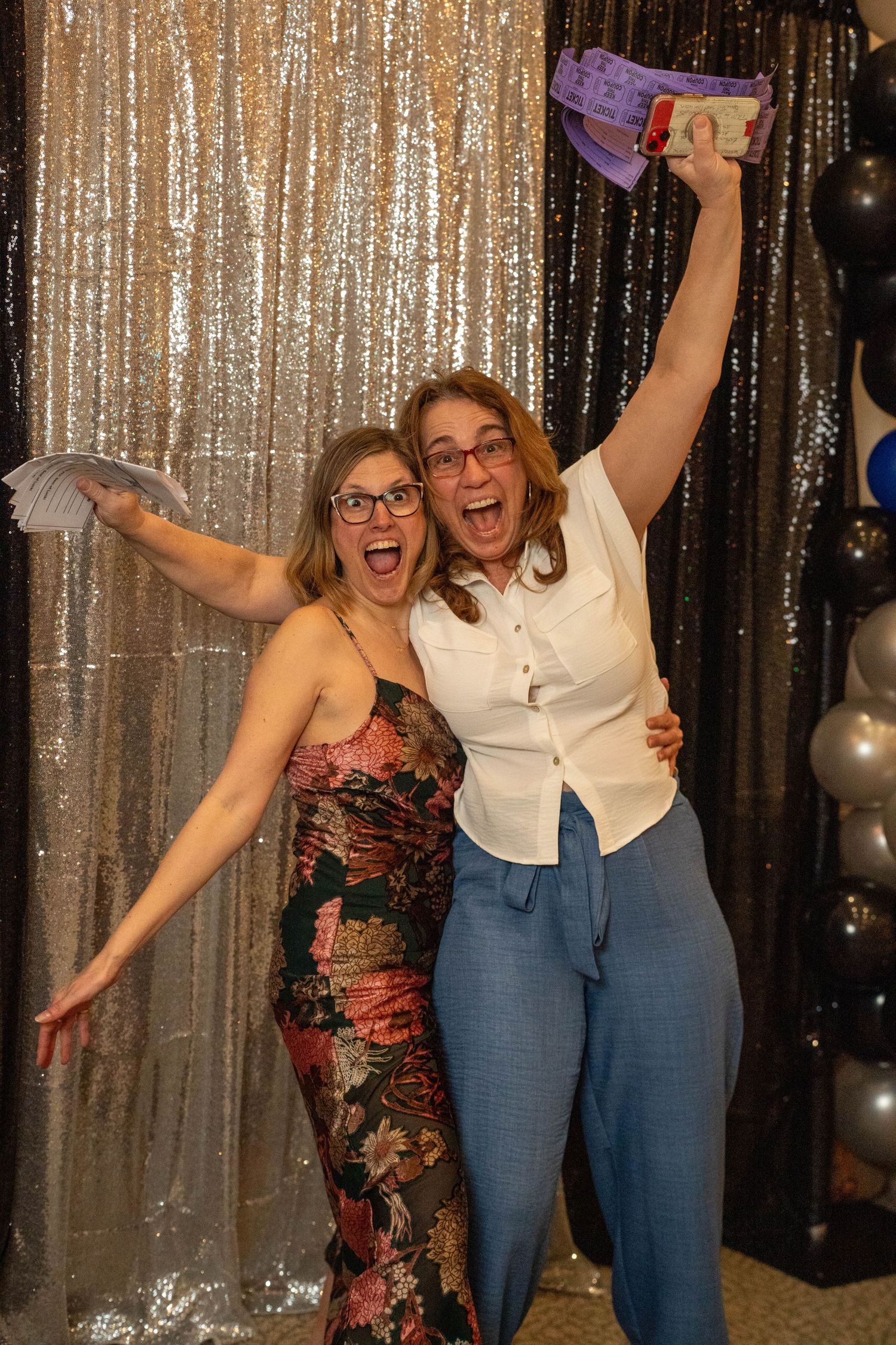 Two people celebrating with champagne and rose gold number 5 balloon amid confetti.