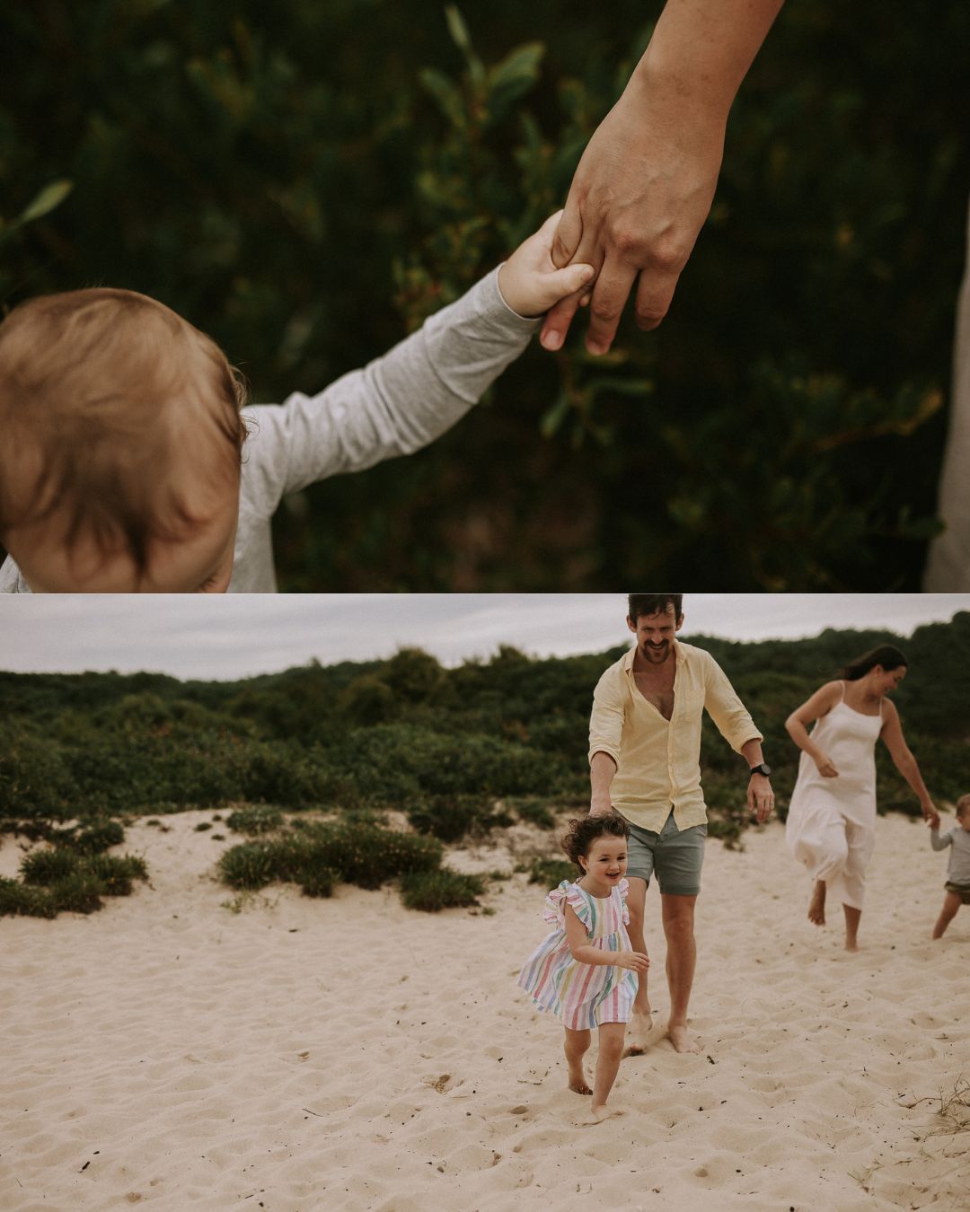 A toddler holds an adult hand on a beach while a family plays on sandy dunes with green shrubs in the background.