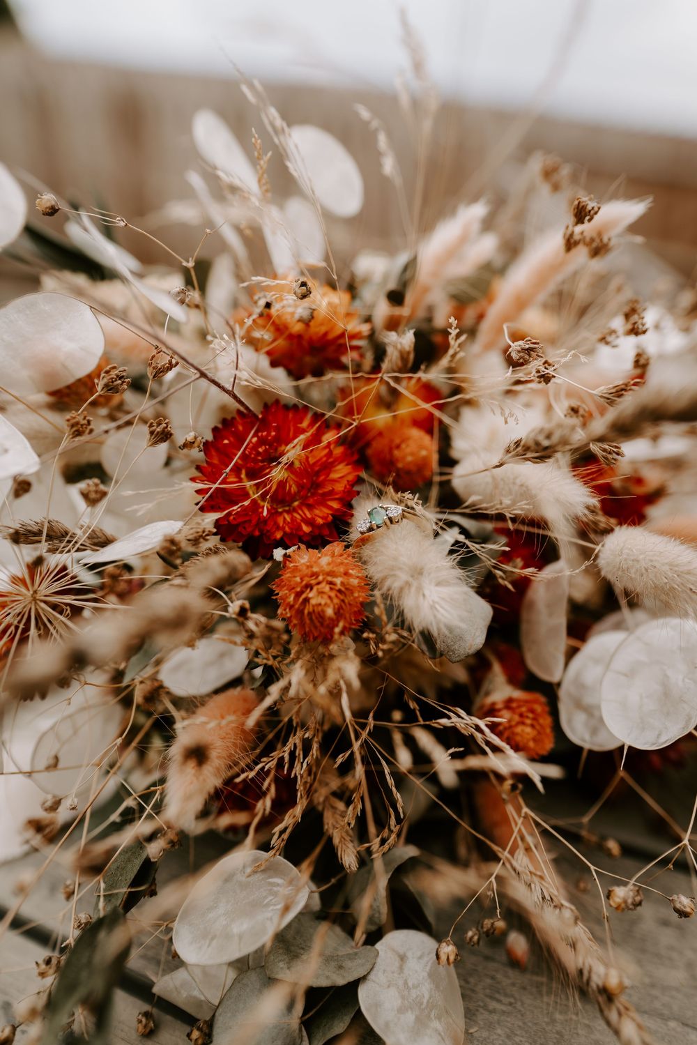 Rustic dried flower bouquet with red dahlias, pampas grass, eucalyptus, and wheat stems in warm autumn tones.