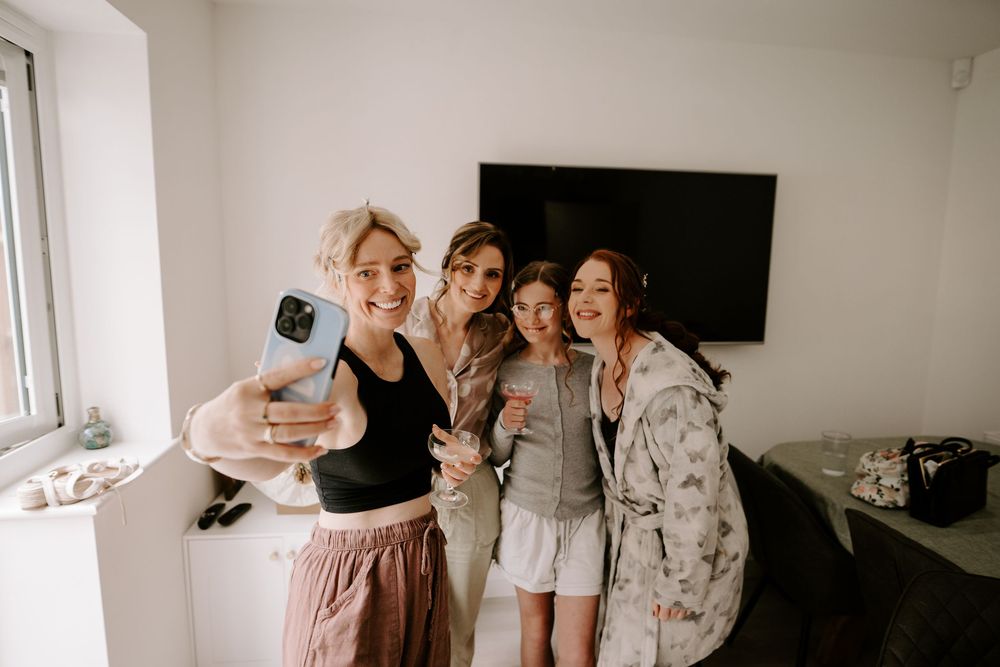 Four bridesmaids taking a selfie together while getting ready for a wedding.