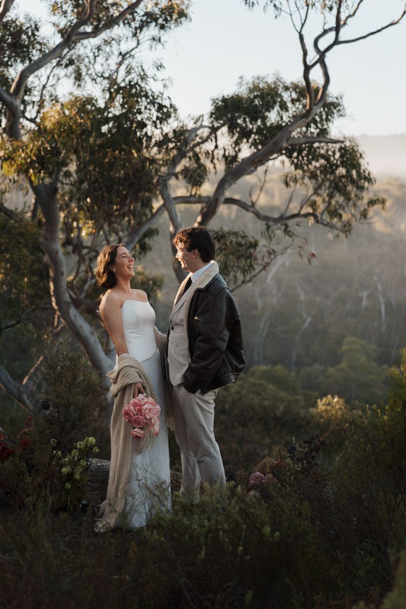 Bride and groom stand together on a misty hillside surrounded by eucalyptus trees, bride holding pink bouquet elopement photoshoot