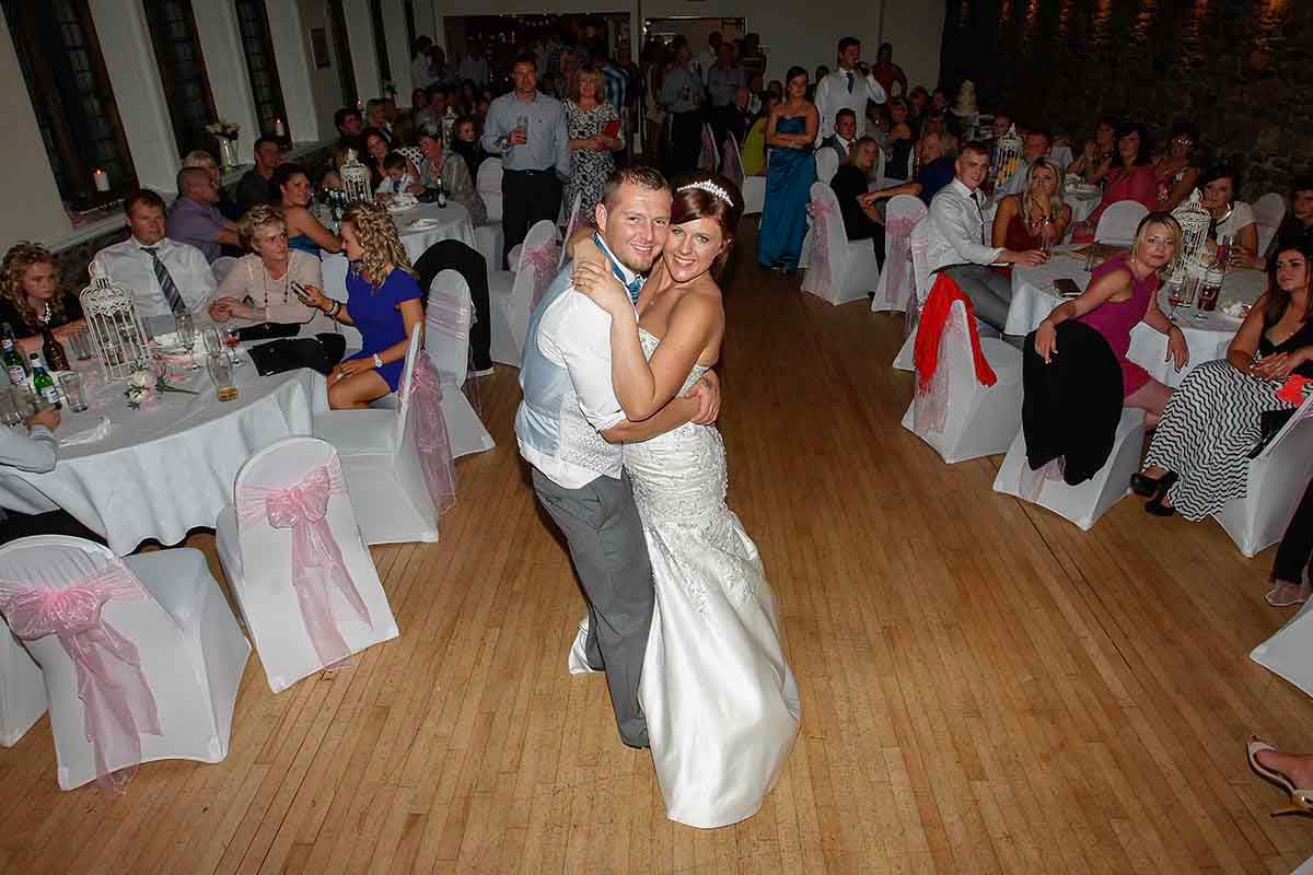 Bride and groom share first dance at wedding reception with guests at the Saints Rooms in Cockermouth