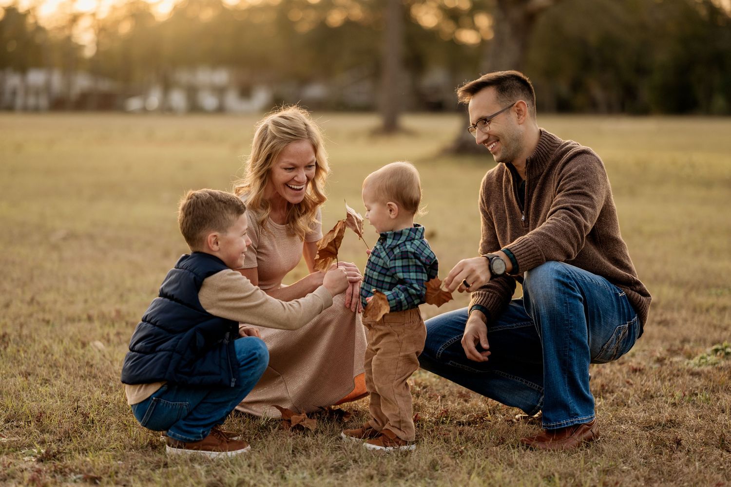 Young boy sitting in fallen leaves during a family photography session in Pensacola, Florida
