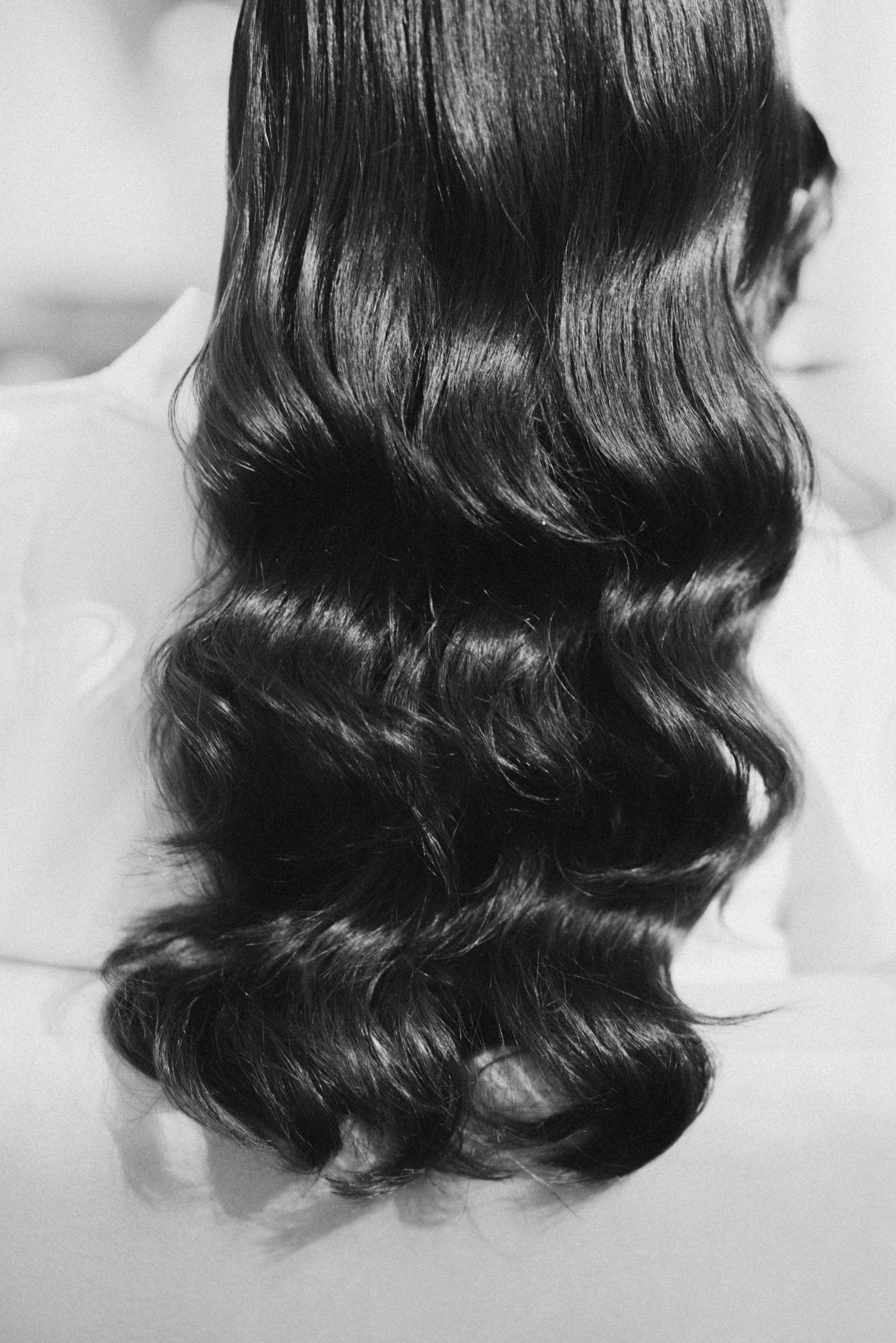 Black and white photo of long, dark, wavy hair cascading down a back with elegant curls.