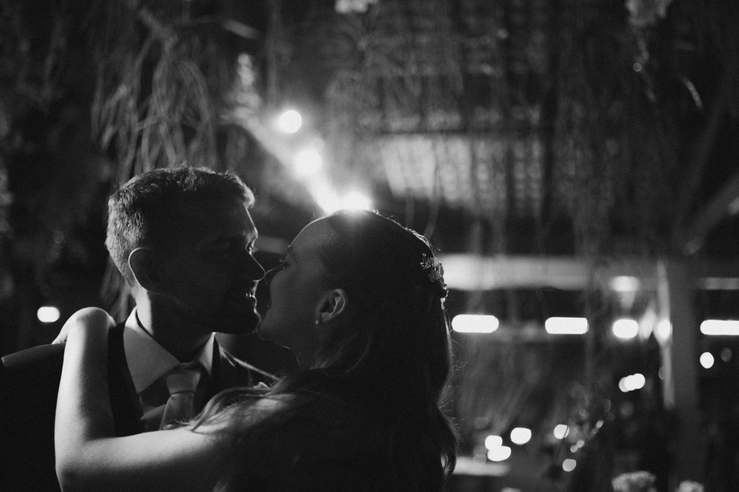 Romantic black and white photo of bride and groom sharing first dance kiss at wedding reception.