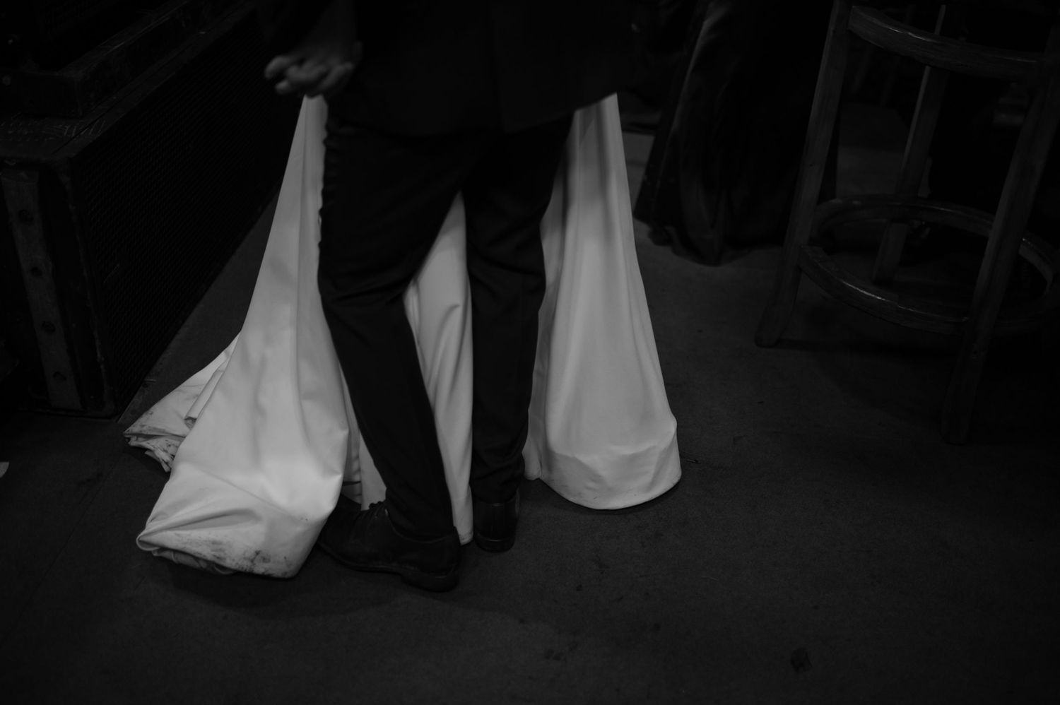 Black and white photo of a person carrying two white plastic bags on a dark floor.