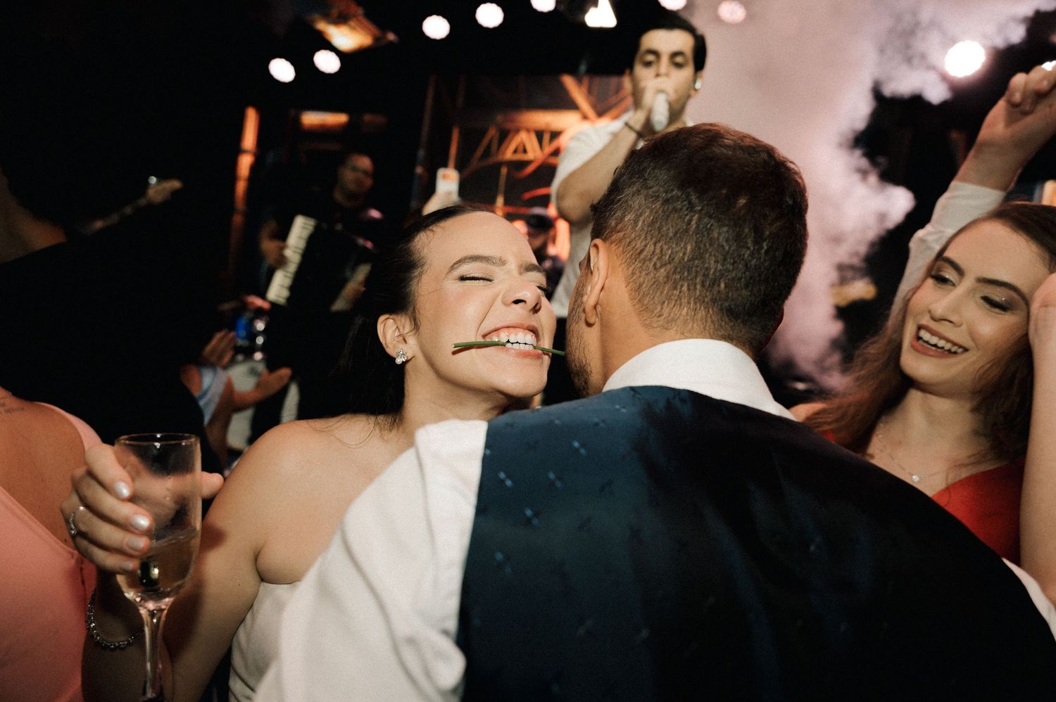 Bride in white dress laughing joyfully while dancing with groom at wedding reception party.