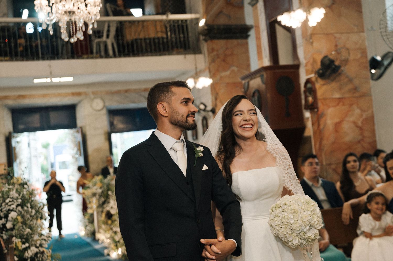 Smiling bride and groom walking down the aisle in an elegant church wedding ceremony.