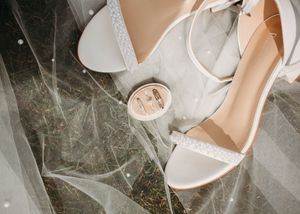 Flatlay details of bridal shoes, bride and groom rings, and pearl veil in Sherwood,MI