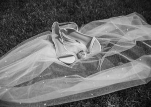 Flatlay details of bridal shoes, bride and groom rings, and pearl veil in Sherwood,MI