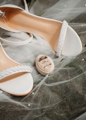 Flatlay details of bridal shoes, bride and groom rings, and pearl veil in Sherwood,MI