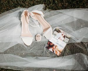 Flatlay details of bridal shoes, bride and groom rings, pearl veil and invitation, in Sherwood,MI
