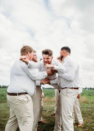 Groom doing spiderman pose while being tossed in the air, in Sherwood, MI