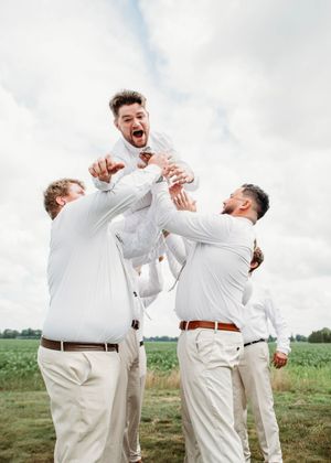 Groom doing spiderman pose while being tossed in the air, in Sherwood, MI