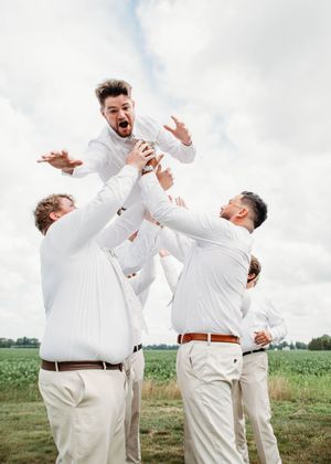 Groom doing spiderman pose while being tossed in the air, in Sherwood, MI