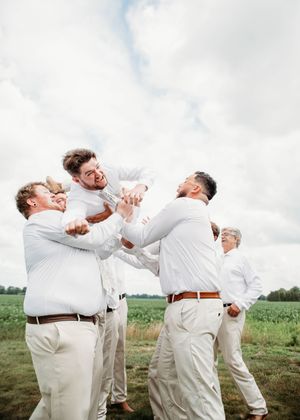Groom doing spiderman pose while being tossed in the air, in Sherwood, MI
