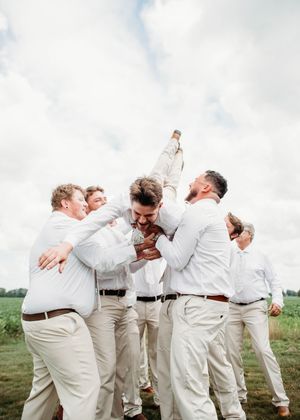 Groom doing spiderman pose while being tossed in the air, in Sherwood, MI