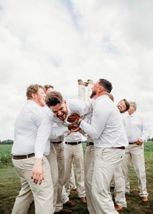 Groom doing spiderman pose while being tossed in the air, in Sherwood, MI
