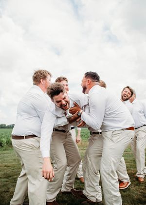 Groom doing spiderman pose while being tossed in the air, in Sherwood, MI