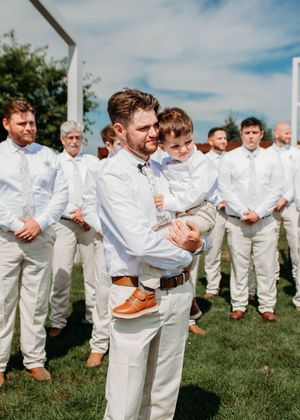 Groom holding child during ceremony, getting emotional as bride walks down the aisle in Sherwood,MI
