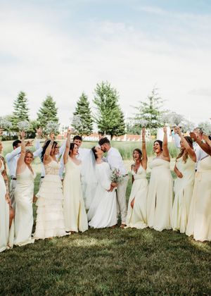 Bride and Groom kissing during portraits with bridesmaids and groomsmen cheering them on in Sherwood,MI