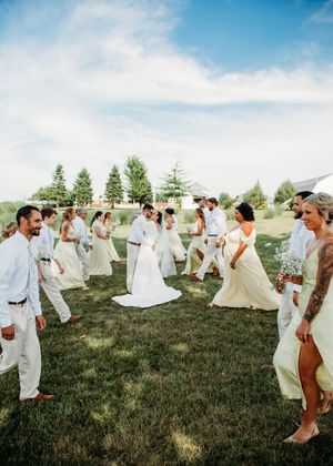 Bride and Groom kissing during portrait with bridesmaids ang groomsmen walking front of them for a unique photo in Sherwood,MI