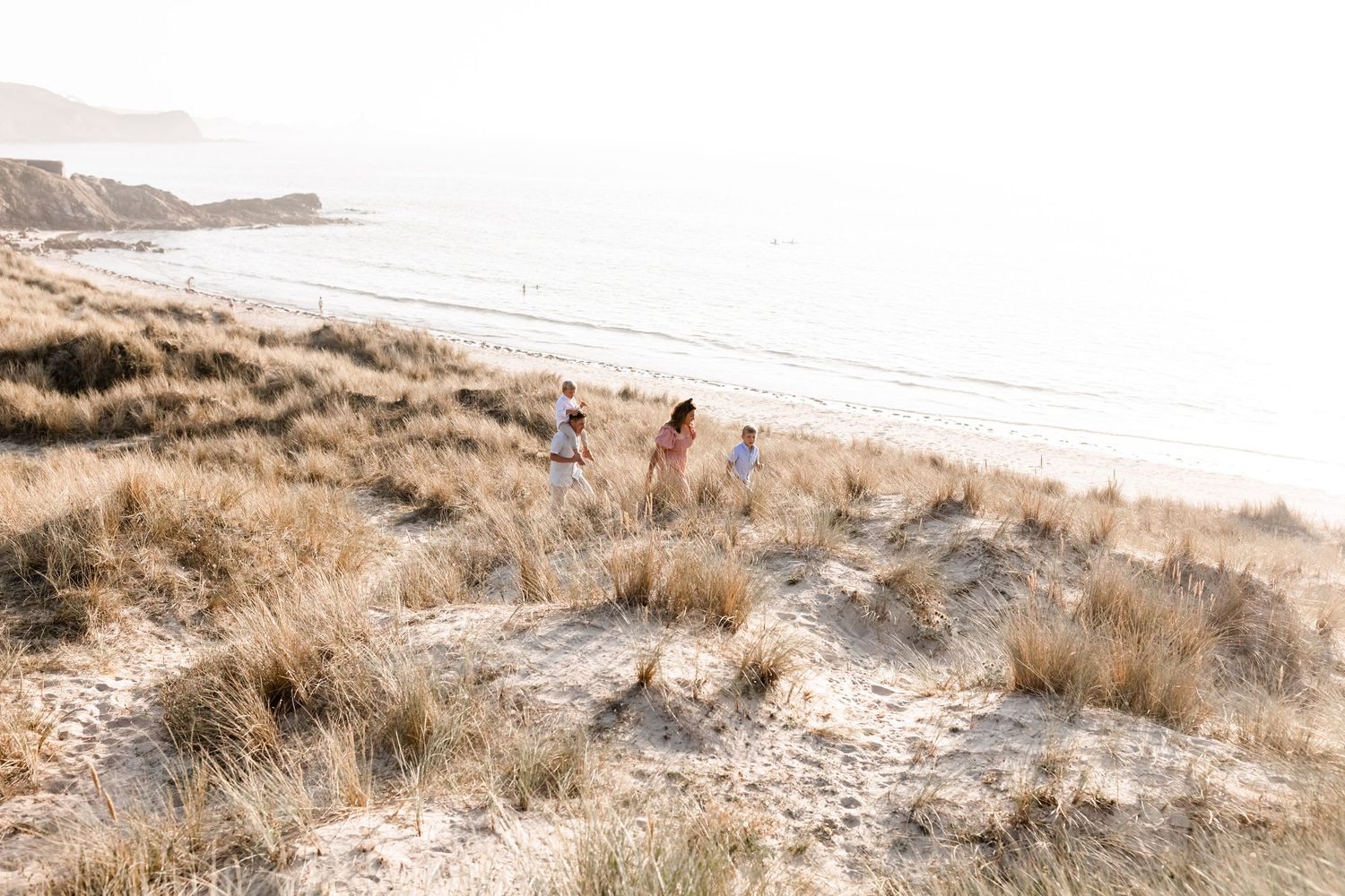 Coastal landscape with sandy dunes and ocean views in soft natural lighting.